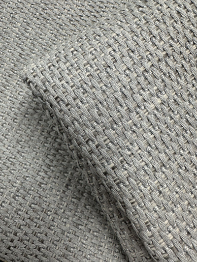 Close-up of Super Cheap Fabrics’ Bacchus Silver upholstery (145cm), showing its textured grid-like weave. A folded section highlights the intricate pattern and premium quality of this light grey Australian fabric.