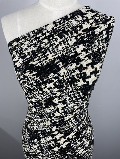 A close-up of a mannequin in a one-shoulder dress made from Super Cheap Fabrics' Printed Lycra - Blotched (150cm), featuring a black and white abstract pattern on two-way stretch polyester spandex, set against a plain background.