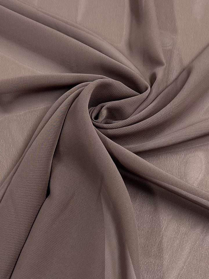 A close-up of Hi-Multi Chiffon in Shitake from Super Cheap Fabrics displays its soft, lightweight polyester fabric with a subtle sheen and spiral pattern, ideal for delicate garments or drapery. Width: 150cm.