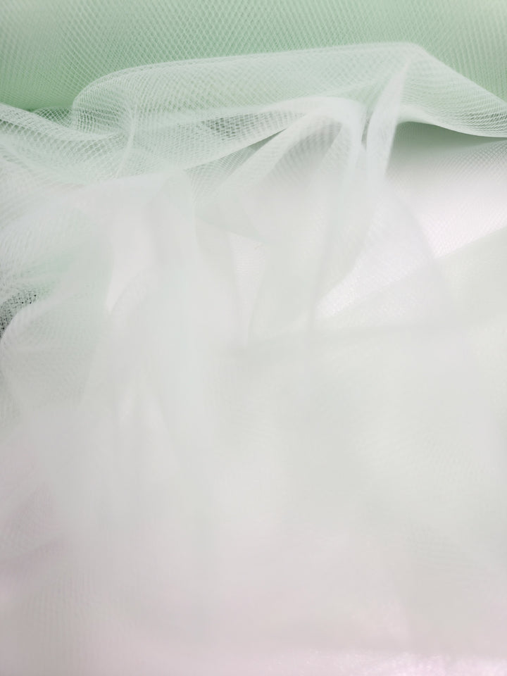 Soft Tulle - Patina Green by Super Cheap Fabrics (150cm) features delicately draped, sheer fabric in a gentle green shade—ideal for bridal veils or whimsical costumes—shown here against a white background.
