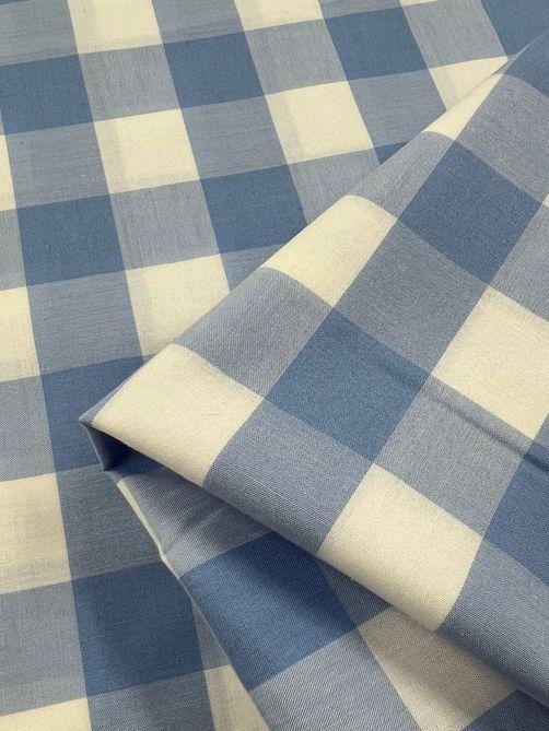 Close-up of Super Cheap Fabrics' Cotton Gingham XL - Windsurfer, showcasing a blue and white checkered, lightweight fabric folded neatly. The pattern features alternating square blocks that form a classic gingham design. With a smooth texture, the fabric appears to be made from printed natural cotton fibers and measures 112cm in width.