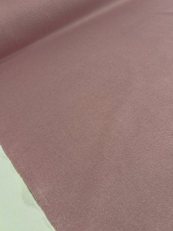 A close-up image of Zephyr, a pink, extra heavy weight Wool Cashmere fabric from Super Cheap Fabrics, showcasing its smooth and soft texture. The fabric appears slightly folded in the background. The edge of the Wool Cashmere - Zephyr is visible at the bottom, revealing part of a lighter surface underneath. For best care, dry clean only.