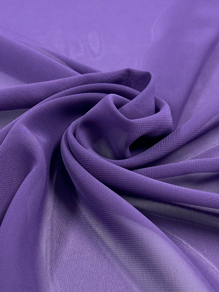 A close-up of Super Cheap Fabrics' Hi-Multi Chiffon in Wineberry, elegantly spiraled. The 150cm lightweight material is smooth with a slight sheen, offering a rich, vibrant look. Shadows and folds add depth to the scene.