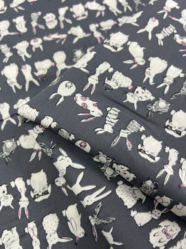 The Printed Cotton - Bunny Mayhem - 120cm by Super Cheap Fabrics features a whimsical pattern of white and pink illustrated rabbits and llamas, each with unique accessories like scarves and bows. Crafted from natural cotton fibers, this fabric is ideal for creating charming clothing and household items.