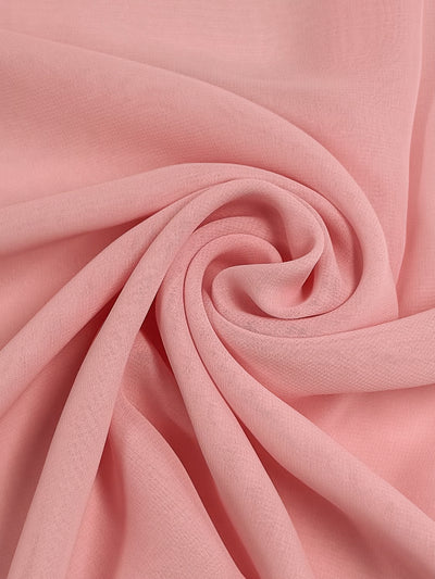 A close-up of the Hi-Multi Chiffon in Tickled Pink by Super Cheap Fabrics reveals its smooth, elegant texture swirled into a spiral pattern with gentle folds.