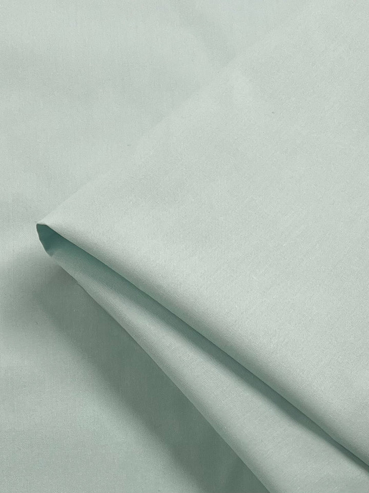 A close-up of Super Cheap Fabrics' Plain Cotton - Cooling Oasis - 156cm in light mint green shows its smooth, soft texture and lightweight feel—ideal for creating a cool, comfortable oasis.