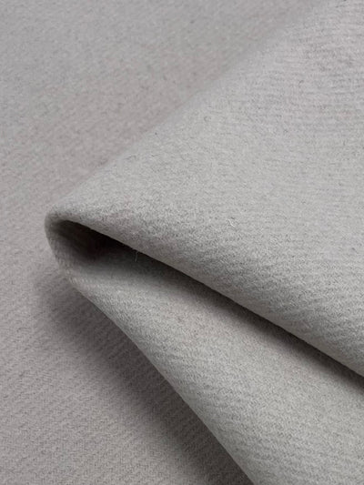 Close-up of folded Designer Wool - Tapioca by Super Cheap Fabrics, 150cm wide; a light gray fabric with subtle texture that looks smooth and slightly cushioned, ideal for cozy clothing or upholstery.