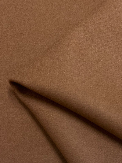 A close-up of Super Cheap Fabrics' Merino Wool - Clove - 150cm shows smooth, soft brown fabric with gentle folds and a slightly fuzzy surface. The cozy heavy-weight fabric is perfect for garments or upholstery, enhanced by its moisture-wicking versatility.