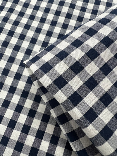 Close-up of folded, lightweight Cotton - Navy Gingham - 145cm from Super Cheap Fabrics. The 100% cotton material features evenly spaced squares creating a classic gingham design.