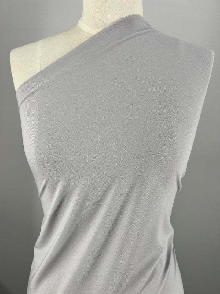 Close-up of the ITY Knit - Silver fabric from Super Cheap Fabrics displayed on a mannequin against a plain background. The medium-weight knit drapes smoothly, highlighting its soft texture and elegant design.