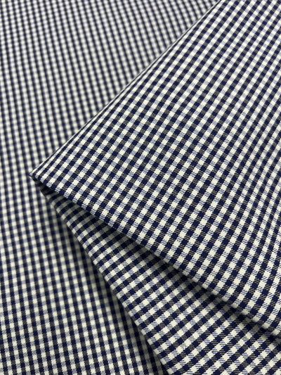 Close-up of the **Super Cheap Fabrics** Cotton Drill - Mini Gingham, a 150cm wide fabric featuring a small blue and white checkered pattern. The lightweight cotton drill is neatly arranged to showcase its finely detailed grid-like design.