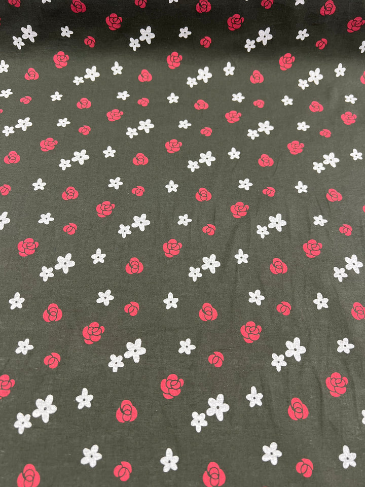 The Linen Voile - Roses - 145cm by Super Cheap Fabrics features a dark green background adorned with small, scattered red rose patterns and white floral icons. The design is evenly distributed, creating a charming, intricate pattern perfect for home decor while ensuring breathability.