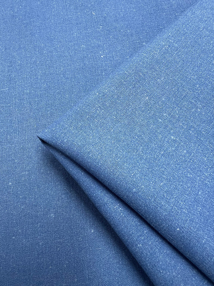 Close-up view of the Linen Blend - Denim - 147cm by Super Cheap Fabrics, showcasing a neatly folded textile featuring a fine, textured weave. The surface displays subtle tone variations, enhancing its soft and elegant appearance ideal for upholstery.