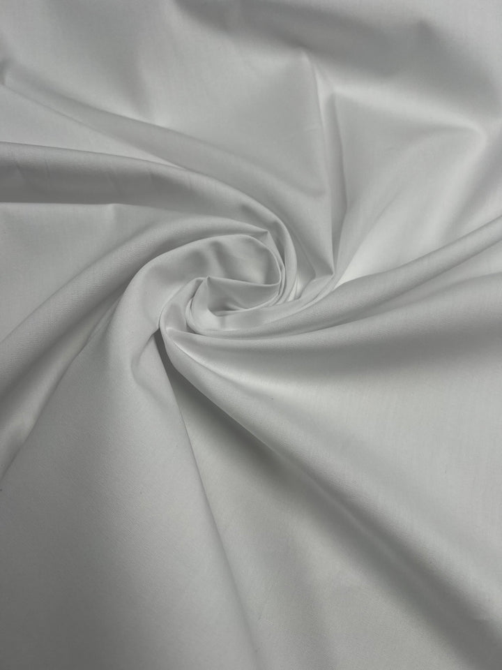 A close-up of the GOTS Cotton - White from Super Cheap Fabrics, showcasing its lightweight texture and spiral drape in the center, resulting in a smooth and flowing appearance.