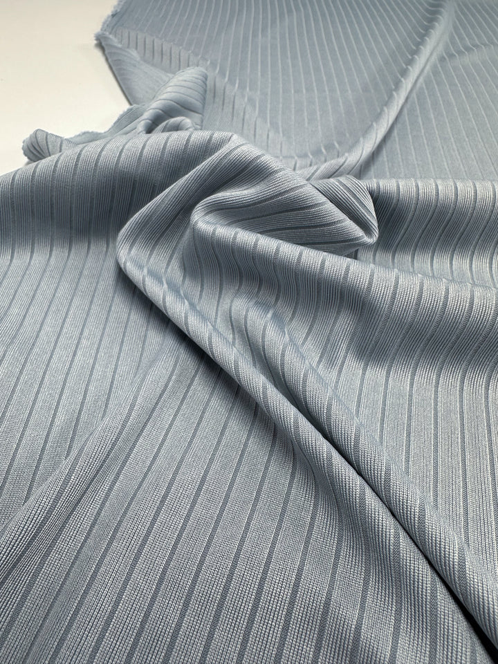 A close-up of the Super Cheap Fabrics' Rib Knit in Pearl Blue (170cm), showcasing its soft, medium weight texture. The fabric is smoothly draped with vertical lines and a subtle sheen, enhancing the gentle folds and wrinkles.