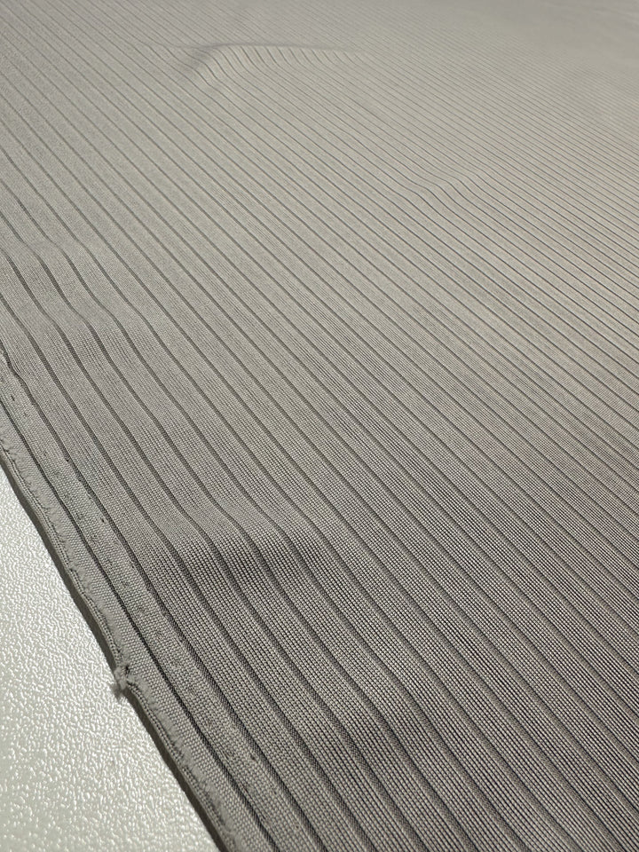 Close-up of Super Cheap Fabrics' Rib Knit in Grey, 175cm wide, showcasing medium-weight rib knit lines on a flat surface. The fabric features textured, parallel design with generous stretch, enhancing its versatile appeal.