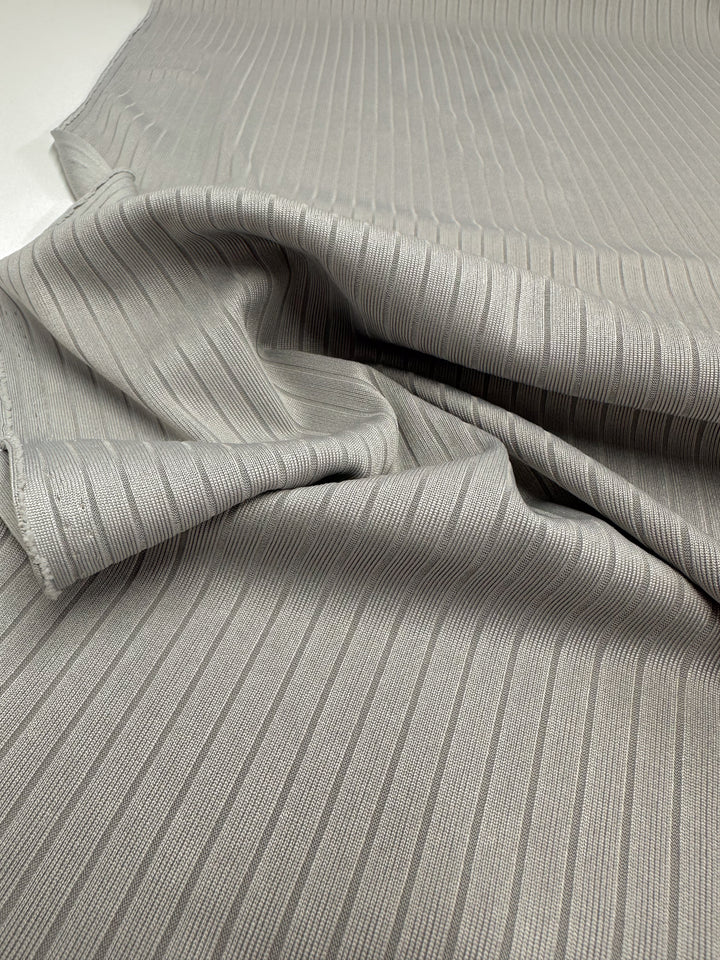 A detailed view of Super Cheap Fabrics' Rib Knit in Grey (175cm) highlights its medium weight, horizontal stripes, and soft texture with gentle folds and a subtle sheen.