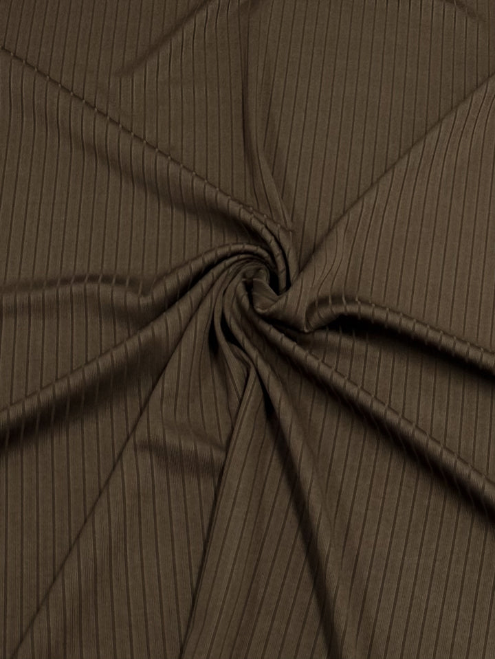 The Super Cheap Fabrics "Rib Knit - Pinecone - 170cm" displays a brown, medium-weight texture with spiral folds radiating from the center, creating a dynamic and swirling look.