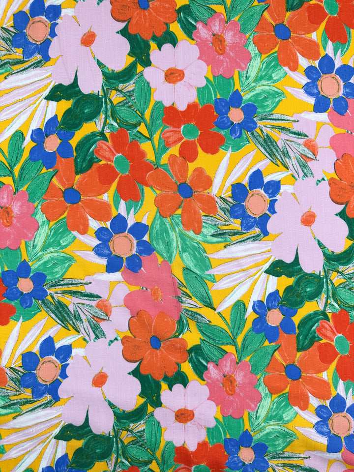 The Bamboo Rayon - Florita - 145cm by Super Cheap Fabrics showcases a vibrant floral pattern with large pink, red, and blue flowers on a bright yellow background. This lightweight fabric is colorful and dense, making it ideal for multi-use applications.