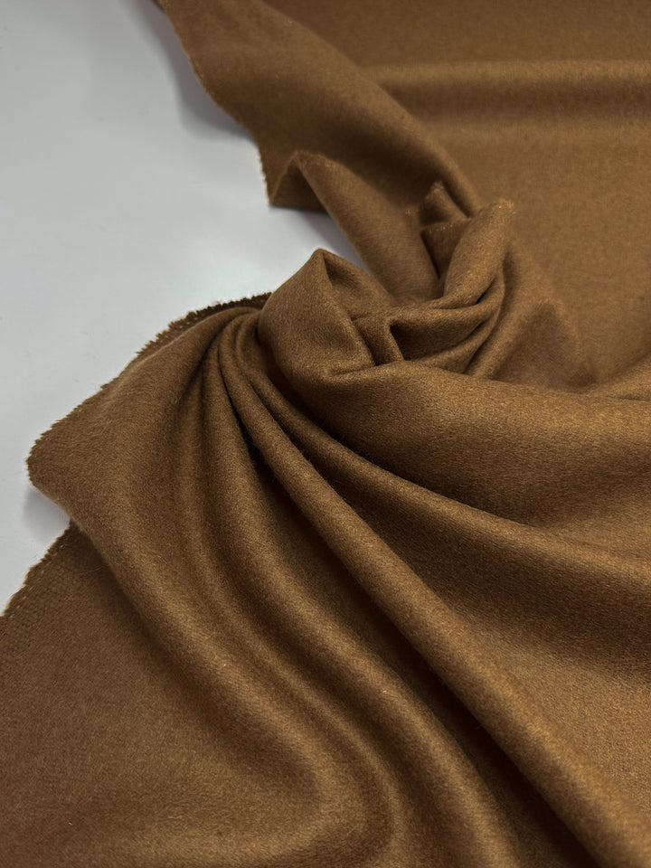 A close-up of the Super Cheap Fabrics Wool Cashmere - Nuthatch - 150cm, showcasing its luxurious softness in gentle folds against a white background, highlighting its smooth and plush appearance.