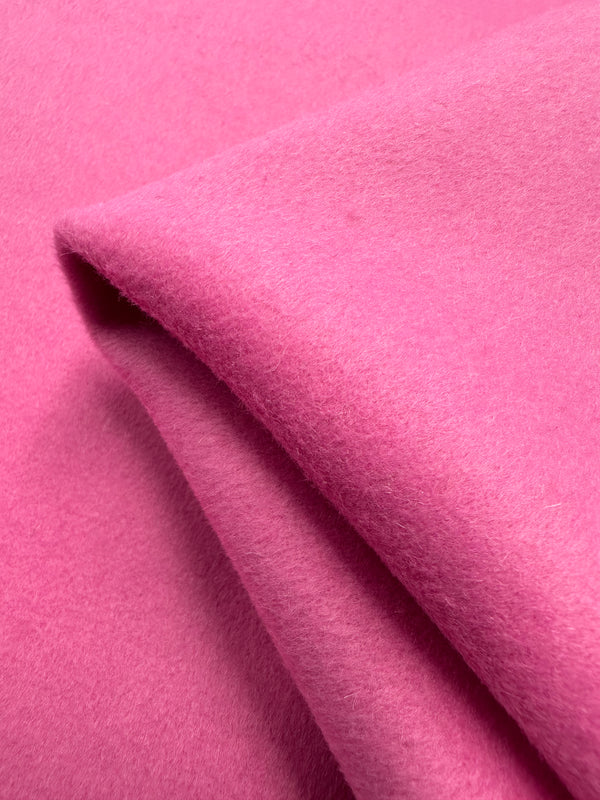 Close-up of a folded piece of Wool Cashmere - Fiji Flower by Super Cheap Fabrics. The 150cm fabric displays luxurious softness, velvety texture, and a vibrant pink hue dominating the image.