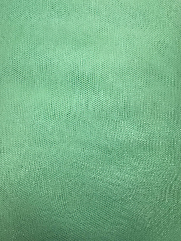 Close-up of Super Cheap Fabrics’ Soft Tulle in Patina Green (150cm): a textured fabric with fine, crisscrossing lines and a subtle wavy pattern, perfect for bridal veils or costume projects.