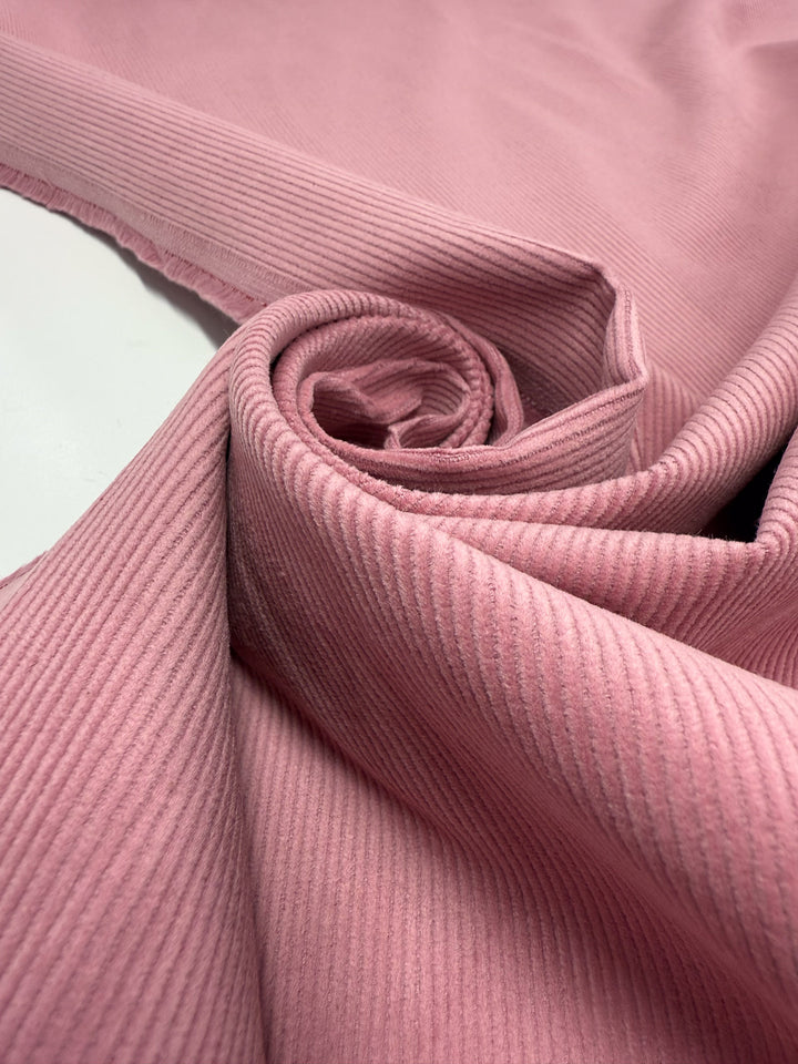 A close-up of Pin Wale Corduroy - Blush (147cm) by Super Cheap Fabrics shows its soft, textured lines and gentle folds—ideal for cozy winter wear.