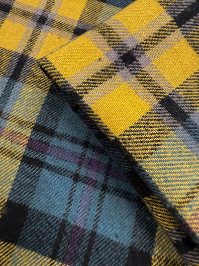 Close-up of two overlapping Flannel Plaid - Highland Dusk fabrics by Super Cheap Fabrics. These medium-weight cotton flannels in yellow, black, grey, and light blue tartan are ideal for shirts. Width: 145cm.