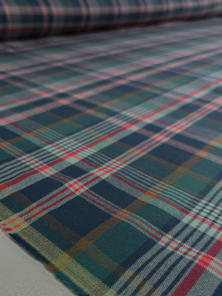 A close-up of Super Cheap Fabrics' Flannel Tartan - Glenmore Forest (145cm), featuring lightweight flannel with a blue, green, red, and white plaid pattern laid flat for a timeless heritage look.