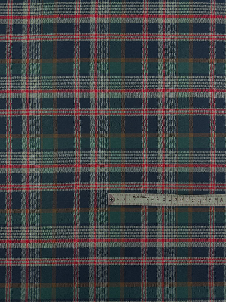 A ruler in centimeters is placed on Super Cheap Fabrics’ Flannel Tartan - Glenmore Forest (145cm), showing the scale and detail of its classic green, navy, white, red, and brown plaid heritage pattern.