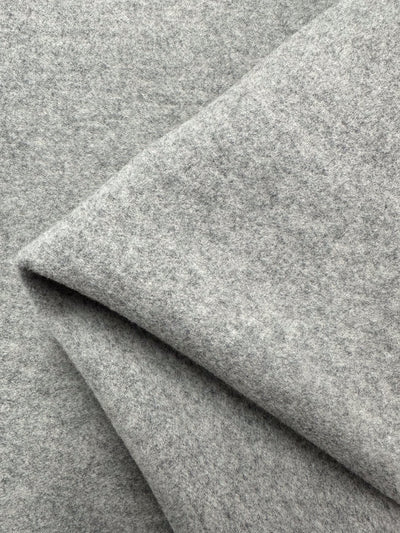 Close-up view of a soft, folded Wool Flannel - Ultimate Gray from Super Cheap Fabrics. The light gray fabric has a smooth, felt-like texture. The folds create subtle shadows, adding depth and richness to this material, which is often used in high-quality coats and jackets.