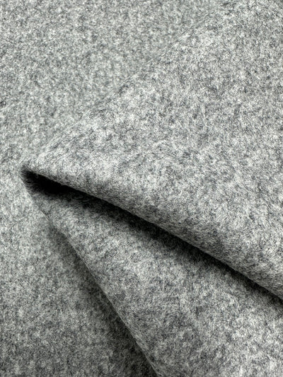A close-up image of a folded piece of the Virgin Wool - Gargoyle - 140cm fabric by Super Cheap Fabrics. The texture is soft and fuzzy, featuring a slightly mottled appearance. Crafted from virgin wool and made in Italy, this heavy weight wool fabric is layered to showcase its thickness and plush quality.