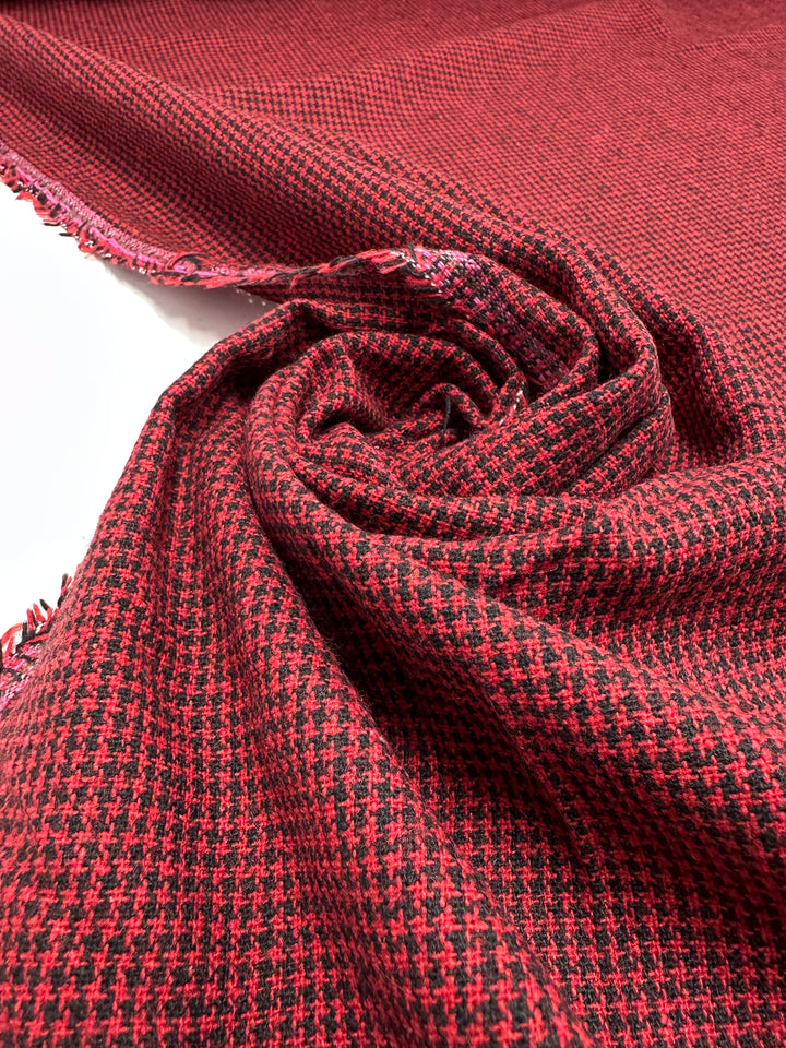 The Designer Tweed - Houndy by Super Cheap Fabrics is a red and black houndstooth medium weight fabric. Rolled out with fringed edges, its texture is visible, making this 155cm wide fabric ideal for stylish outer coats.