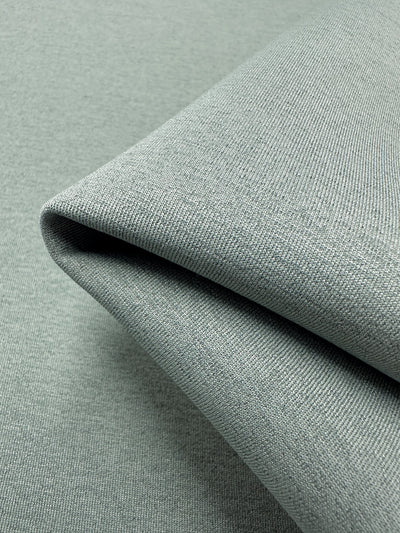 Close-up of neatly folded, light gray Scuba Knit - Mermaid - 165cm by Super Cheap Fabrics with a fine, slightly textured weave. The fabric's surface appears smooth and uniform, reflecting a soft sheen under the lighting.