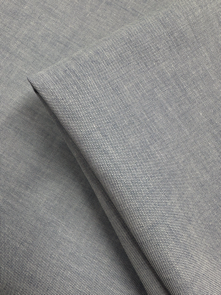 Close-up of Super Cheap Fabrics' Oxford Cotton - Denim (146cm): light gray fabric with fine woven texture, neatly folded to highlight its smooth, detailed weave and enhanced cotton softness.
