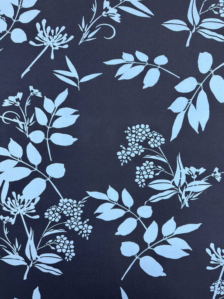 Super Cheap Fabrics’ Printed Lycra - Silhouette Garden - 150cm features light blue botanical silhouettes on a dark background, offering a modern, decorative look with versatile appeal.
