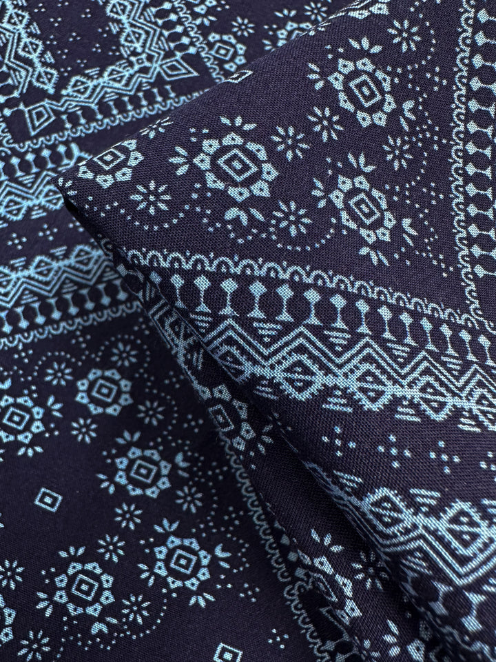 Close-up of Designer Rayon - Navy Nomad by Super Cheap Fabrics, 145cm wide, featuring intricate light blue geometric and floral patterns on dark blue—ideal for vibrant, versatile fabric projects.