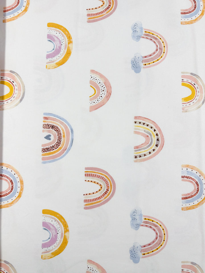 Introducing the Super Cheap Fabrics' Cotton Duck - Rainbow - 112cm. This cotton fabric features an array of vibrant rainbows in soft pastel shades of yellow, pink, blue, and purple set against a light background. Ideal for tote bags or home décor projects, each rainbow showcases distinct textures and designs.