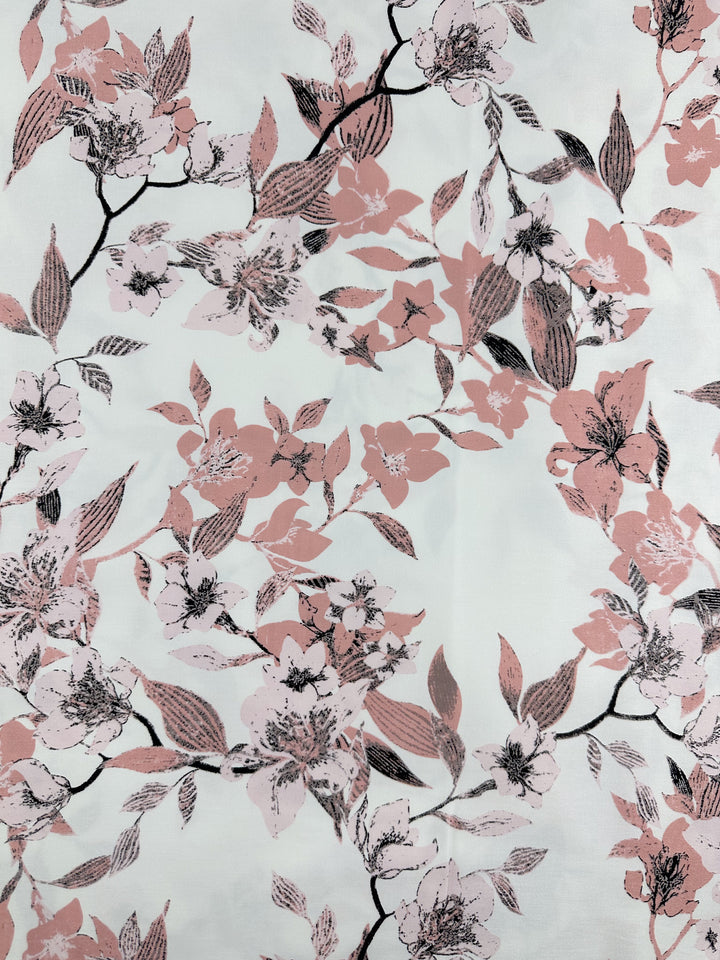 The Cotton Sateen - Lizzy's Garden by Super Cheap Fabrics showcases a lightweight cotton fabric with elegant floral patterns of pink and black flowers, accompanied by delicate leaves on a light background. These flowers are depicted in various stages of bloom, creating a harmonious and sophisticated design ideal for household décor items. The width of this fabric is 128cm.