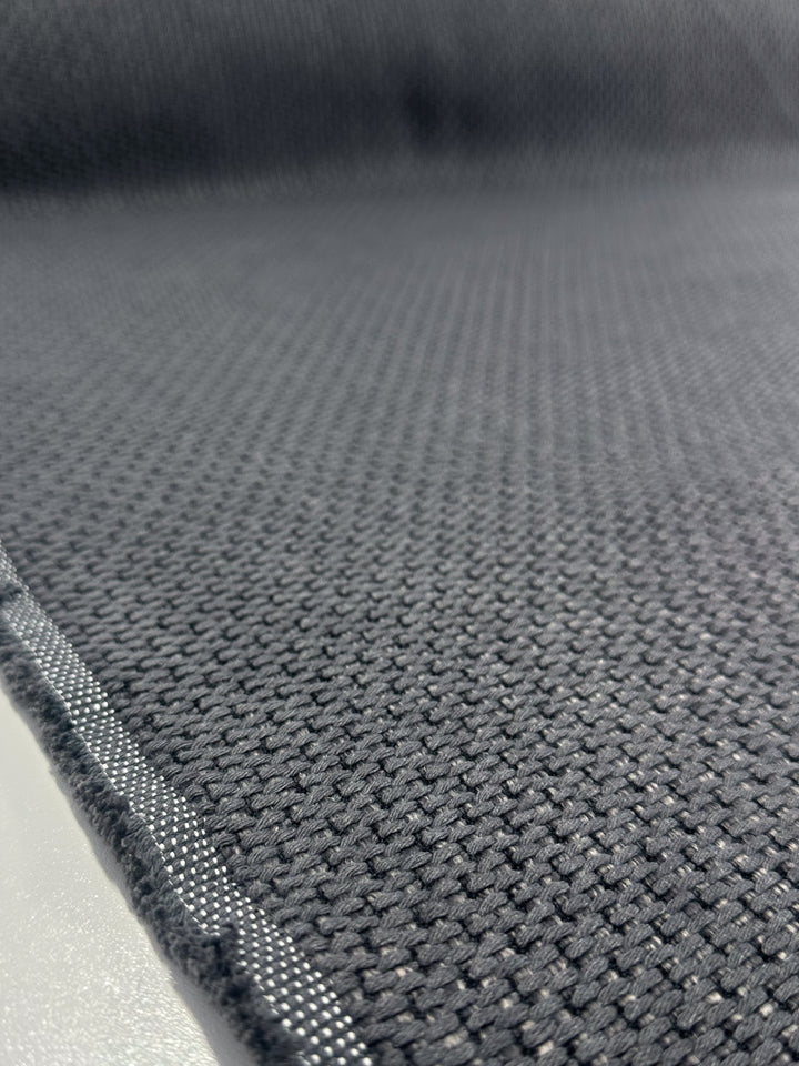 Close-up of Super Cheap Fabrics’ Basketweave Upholstery in Bacchus Blue Steel (142cm), showing its textured, dark grid pattern and a visible seam along the left edge, displayed on a light-colored surface.