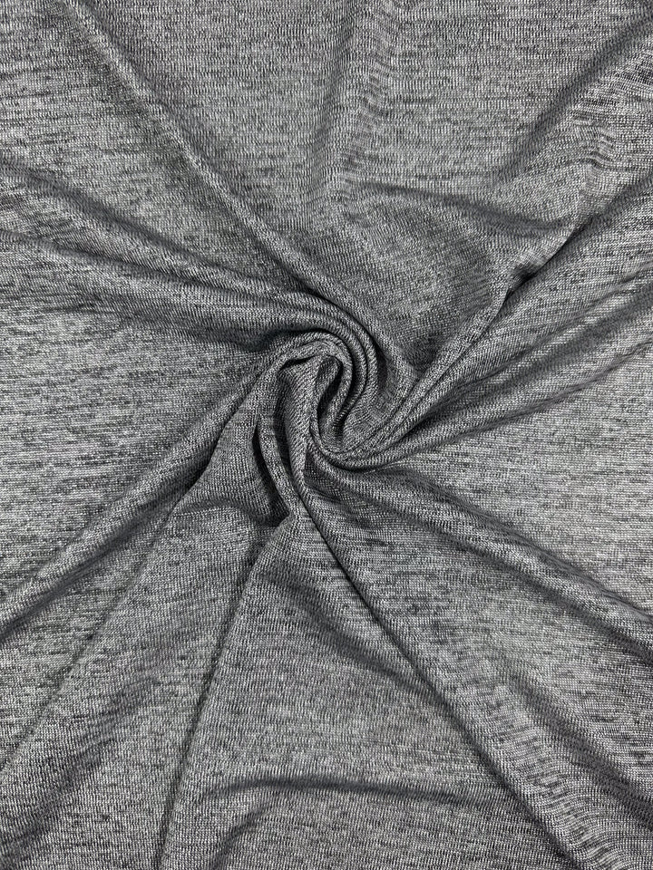 A close-up of Super Cheap Fabrics' Textured Knit - Greyline Lamé (145cm) shows its light gray, soft surface and fine weave twisted into a spiral to highlight the textured knit detail.