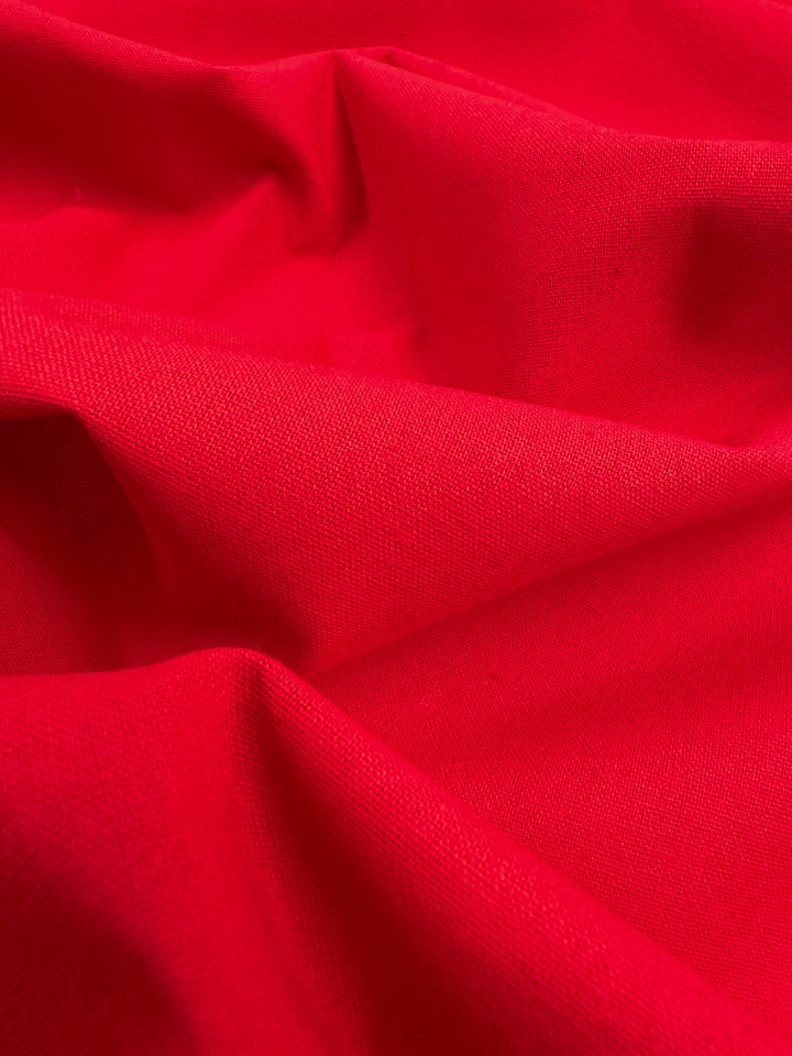 A close-up view of the True Red Ramie Linen from Super Cheap Fabrics, with its folds and visible texture made from natural fibers, creates a dynamic and vibrant visual.