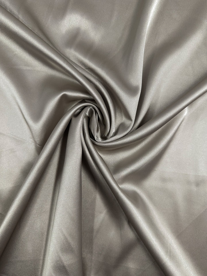 Satin Deluxe - Rock Ridge by Super Cheap Fabrics features a shiny silver-gray luxury fabric with a smooth texture, soft folds, and subtle sheen. Width: 150cm.