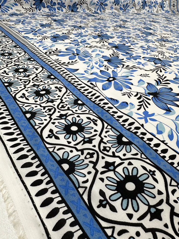 Designer Rayon - Mosaic Valley (145cm) by Super Cheap Fabrics showcases intricate floral and geometric patterns in blue and black on white, inspired by Mediterranean design with stylized flowers and decorative borders.