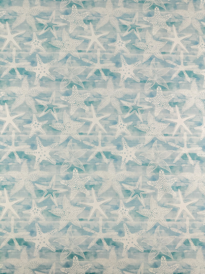 Super Cheap Fabrics' "Printed Cotton - Under The Sea - 150cm" showcases a design of white starfish set against a light blue and white watercolor backdrop. The varying sizes and details of the starfish impart a textured, oceanic aesthetic to the 100% cotton fabric.