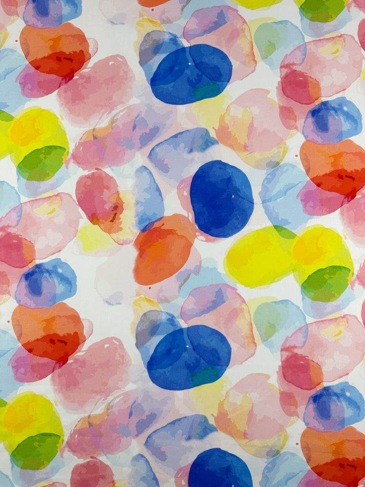 Experience the colorful artistry of Super Cheap Fabrics' Printed Cotton - Bubble, a 150cm fabric showcasing a dynamic watercolor pattern. This design features overlapping blue, yellow, pink, red, and orange circles on a white background. The softly merging circles create an abstract appeal ideal for both clothing and home décor projects.