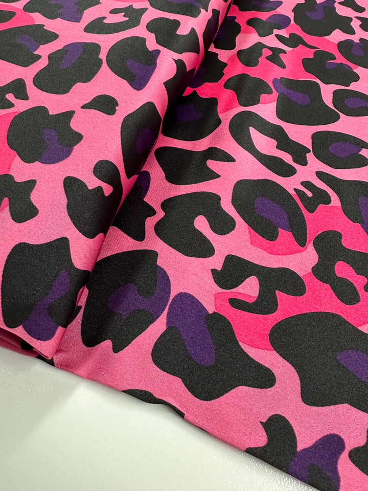 The Silky Satin - Pinky from Super Cheap Fabrics, featuring a pink and black leopard print, provides an elegant touch to any wardrobe with its lightweight satin material.