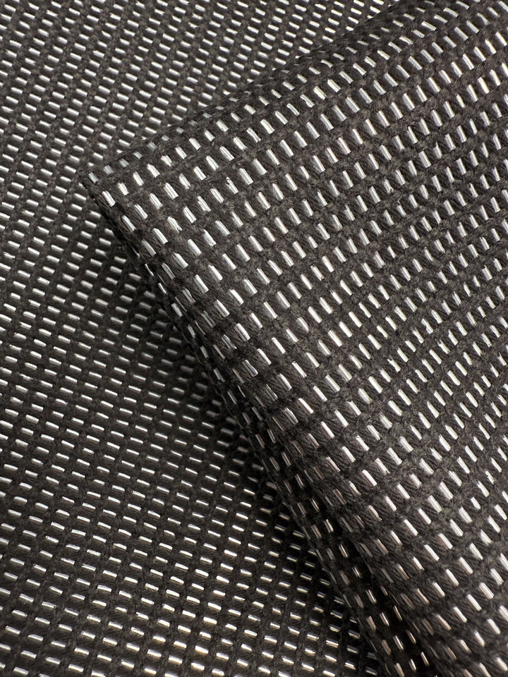 A close-up of Super Cheap Fabrics' Linen Blend - Silver Dash (135cm) highlights its grid pattern of raised, shiny rectangles, with one luxurious piece draped diagonally over another—ideal for sophisticated upholstery projects.
