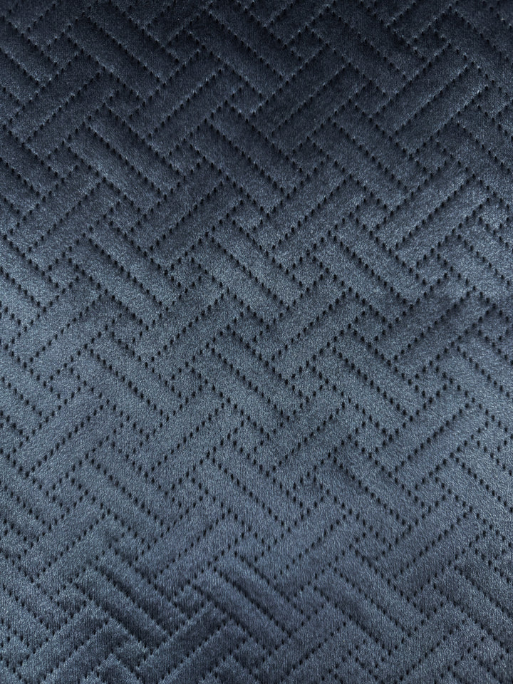 Close-up of Super Cheap Fabrics' Embossed Velvet - Oceana - 150cm: a dark gray quilted fabric with a herringbone pattern and small perforations along the zigzag lines, creating a soft, textured surface with unique design.
