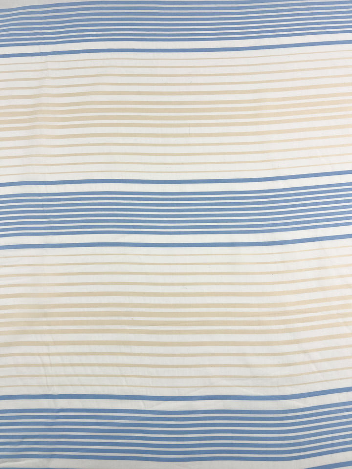 Introducing the GOTS Cotton - Buttercream Stripe - 160cm by Super Cheap Fabrics: This eco-friendly fabric features a stylish pattern of horizontal stripes in shades of blue and beige on a crisp white background. The stripes vary in thickness, alternating between narrow, medium, and thick widths. Made from Certified GOTS Cotton, it perfectly combines trendy design with sustainable fashion.